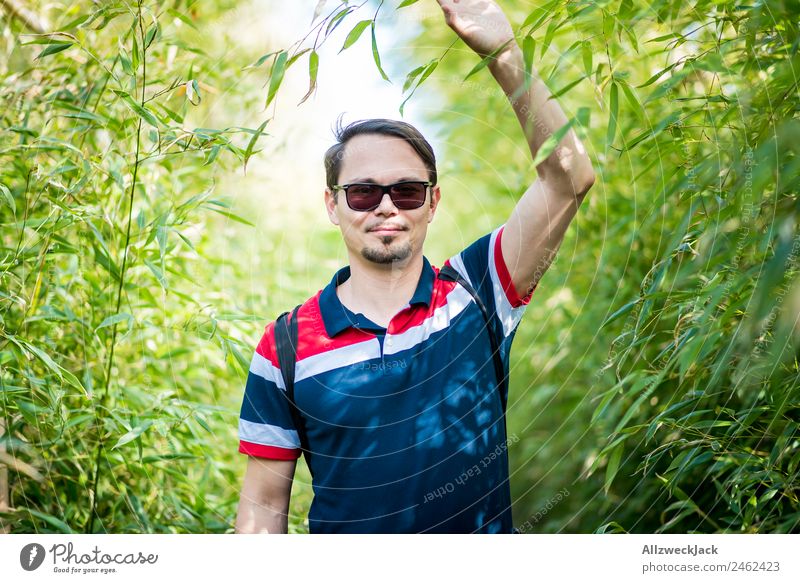 Portrait von einem jungen Mann im Bambus Dschungel Porträt Junger Mann 1 Mensch Sonnenbrille grün Natur Tag Sträucher Blatt Wald Urwald Ferien & Urlaub & Reisen