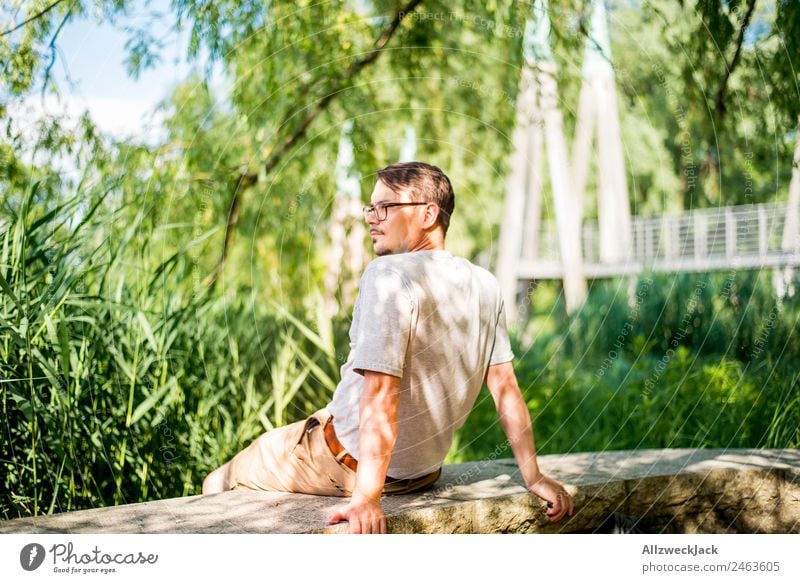 Portrait von einem jungen Mann in der Natur Porträt Junger Mann 1 Mensch Brille grün Tag sitzen Erholung Pause ausruhend genießen Park Ferien & Urlaub & Reisen