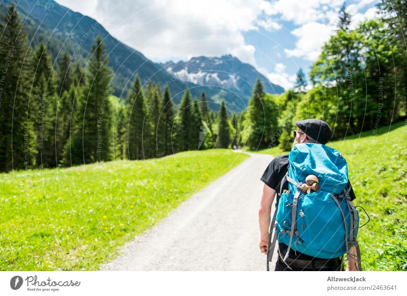 Mann mit Rucksack wandert in den Bergen Tageslicht schönes Wetter Wolken wolkig Natur grün Bäume Wald Idylle Urlaub Reisefotografie Wandern Backpacking Gebirge