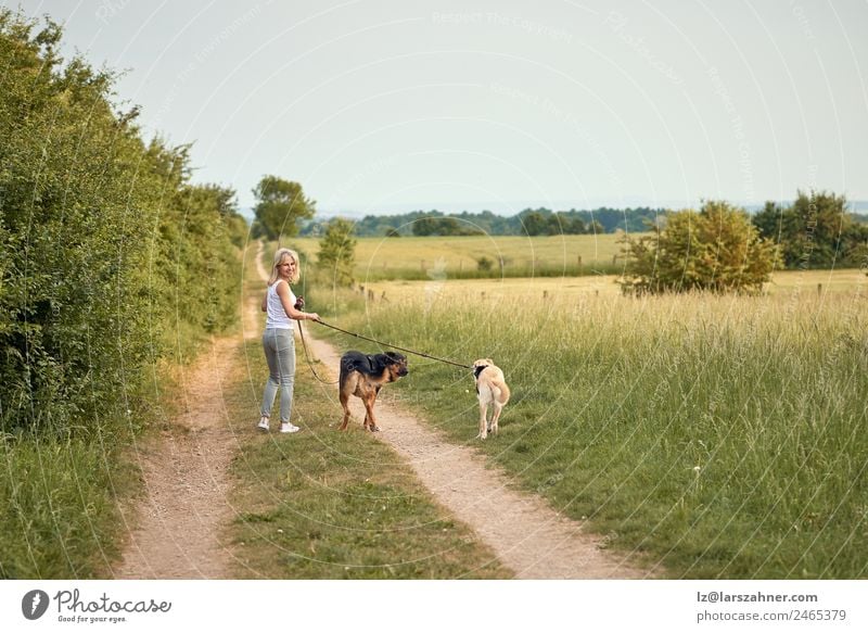 Junge blonde Frau geht mit ihren beiden Hunden spazieren. Lifestyle Glück schön Sommer Erwachsene Freundschaft 1 Mensch Natur Tier Wärme Gras Park Haustier