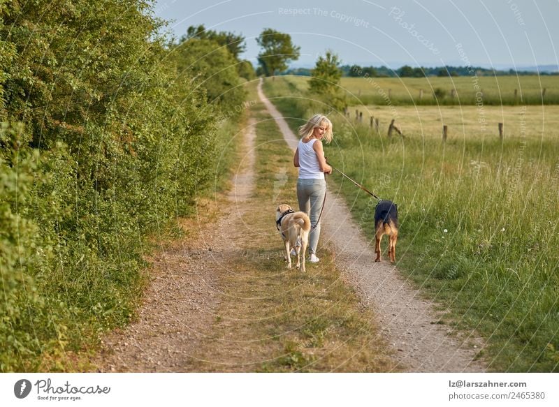 Junge blonde Frau geht mit ihren beiden Hunden spazieren. Lifestyle Glück schön Sommer Erwachsene Freundschaft 1 Mensch Natur Tier Wärme Gras Park Haustier