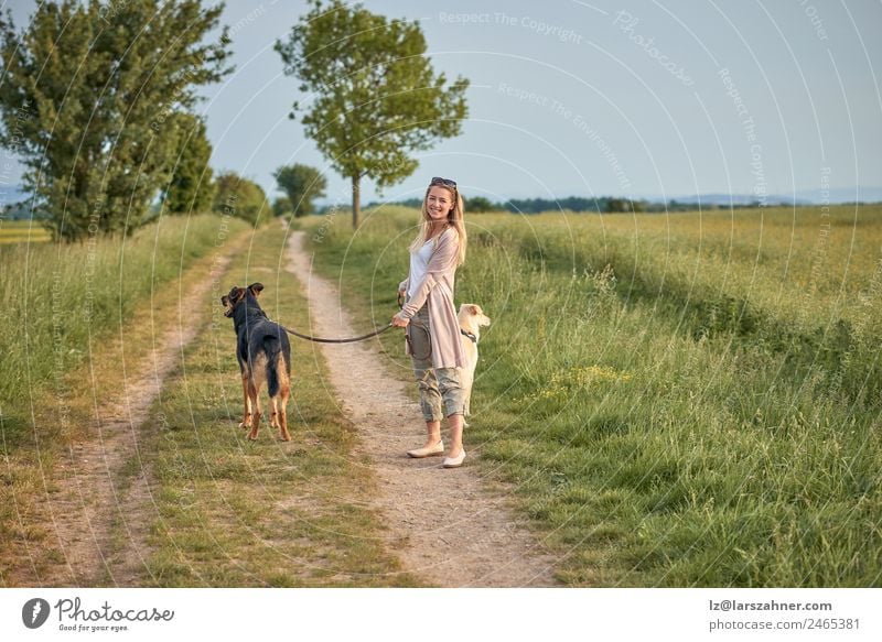 Attraktive lächelnde blonde Frau mit ihren beiden Hunden Lifestyle Glück schön Sommer Erwachsene Freundschaft Natur Tier Wärme Gras Park Haustier Lächeln