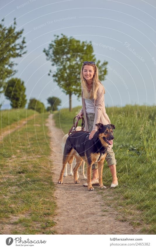 Attraktive lächelnde blonde Frau mit ihren beiden Hunden Lifestyle Glück schön Sommer Erwachsene Freundschaft Natur Tier Wärme Gras Park Haustier Lächeln