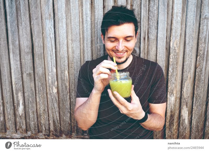 Junger glücklicher Mann genießt einen grünen Smoothie Bioprodukte Vegetarische Ernährung Getränk trinken Erfrischungsgetränk Limonade Saft Milchshake Lifestyle