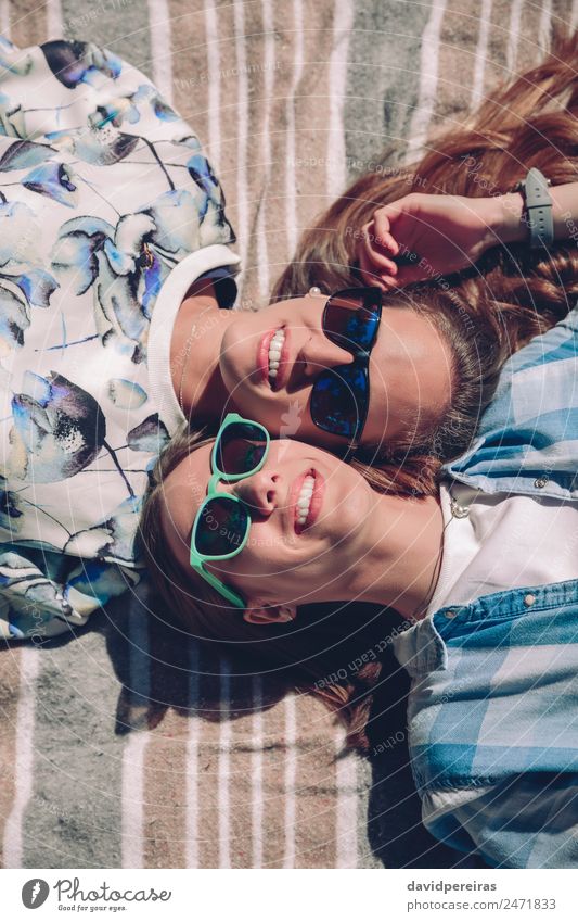 Zwei Frauen mit Sonnenbrille lächelnd in der Decke liegend Lifestyle Freude Glück schön Erholung Freizeit & Hobby Sommer Sonnenbad Mensch Erwachsene