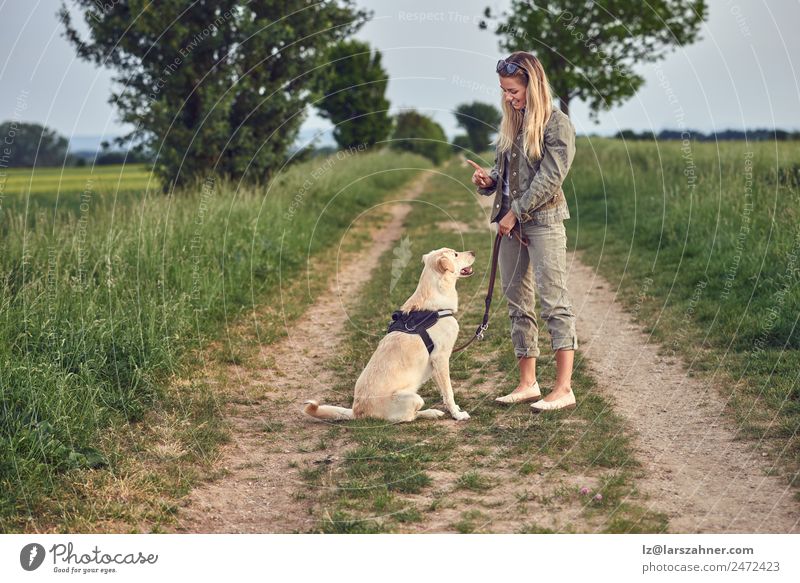 Attraktive junge Frau, die ihren Hund unterrichtet. Sommer Erwachsene Freundschaft 1 Mensch 18-30 Jahre Jugendliche Landschaft Tier Wege & Pfade blond gold
