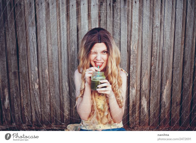 Junge glückliche Frau, die einen grünen Smoothie trinkt. Gemüse Getränk trinken Erfrischungsgetränk Saft Milchshake Lifestyle Stil Freude schön Haare & Frisuren