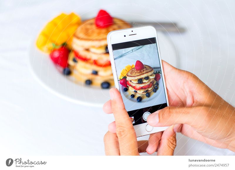 Nahaufnahme der Hände, die ein Foto des Frühstücks mit einem Smartphone machen. Dessert Mittagessen Teller Tisch Telefon Handy Fotokamera Technik & Technologie