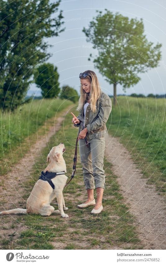 Attraktive junge Frau, die ihren Hund unterrichtet. Sommer Erwachsene Freundschaft 1 Mensch 18-30 Jahre Jugendliche Landschaft Tier Wege & Pfade blond Lächeln