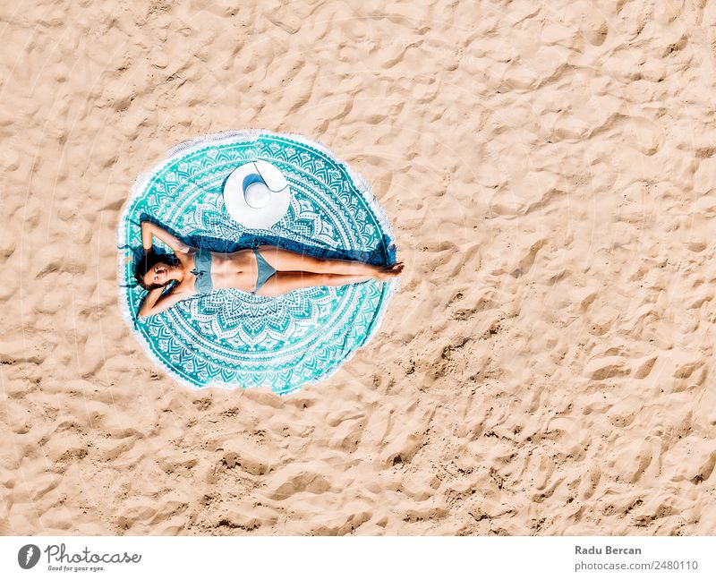 Top Luftdrohne Ansicht der Frau im Badeanzug Bikini Entspannen und Sonnenbaden auf runden türkisfarbenen Strandtüchern in der Nähe des Ozeans Aussicht Handtuch