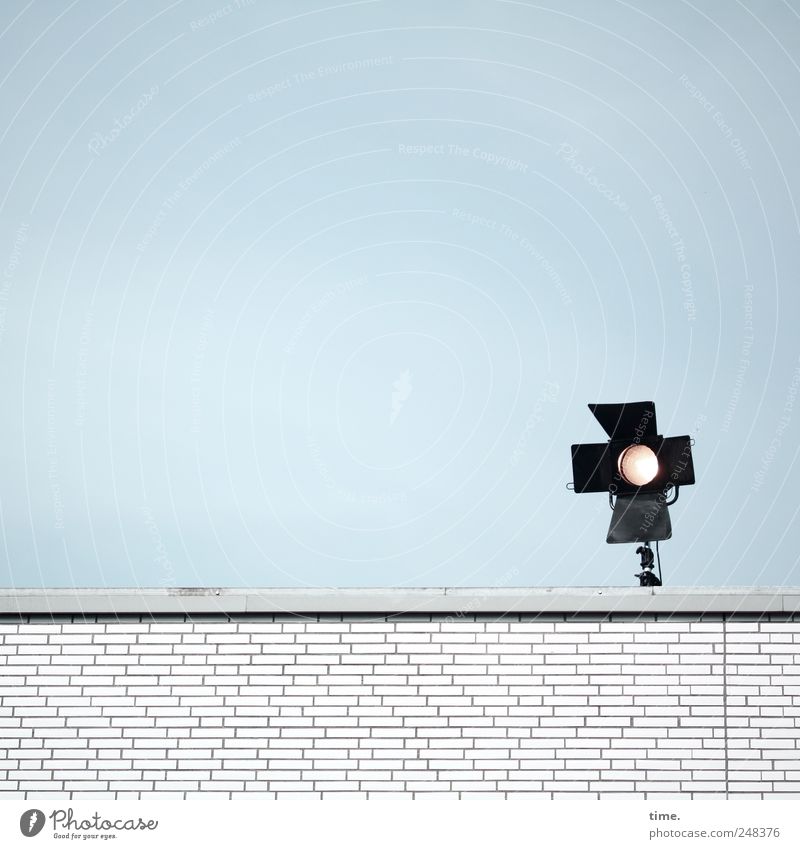 Die unverdrossene Beleuchtung Altonas Mauer Lampe Scheinwerfer Himmel schwarz leuchten Energieverschwendung Umweltverschmutzung weiß Backstein Dach Flachdach
