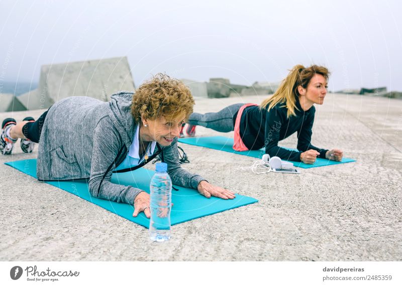 Ältere Frau und Trainerin bei der Plankenübung Flasche Lifestyle Wellness Freizeit & Hobby Sport PDA Mensch Erwachsene Nebel Beton alt Fitness authentisch stark