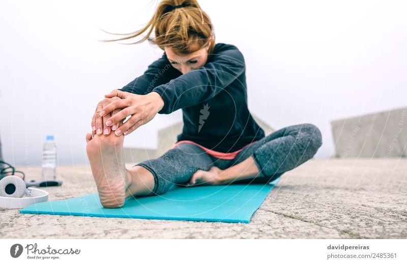 Junge Frau, die ihre Beine am Pier ausstreckt. Flasche Lifestyle schön Wellness ruhig Winter Sport Yoga Mensch Erwachsene Hand Fuß Nebel Beton Fitness