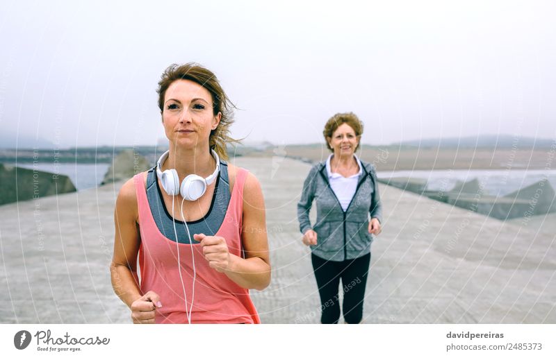 Junge und ältere Sportlerinnen laufen am Seepier Lifestyle Wellness Meer Joggen Mensch Frau Erwachsene Mutter Großmutter Nebel Beton alt Fitness Lächeln