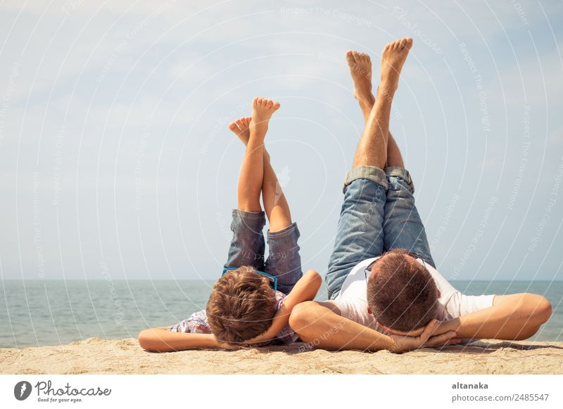 Vater und Sohn spielen zur Tageszeit am Strand. Die Menschen haben Spaß im Freien. Konzept des Sommerurlaubs und der freundlichen Familie. Lifestyle Freude