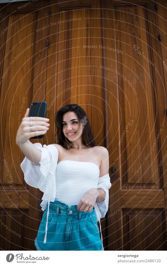 Fröhliche junge Frau mit Selfie auf dem Smartphone Stil Glück schön ruhig Freizeit & Hobby Sommer PDA Technik & Technologie Erwachsene Bekleidung brünett Holz