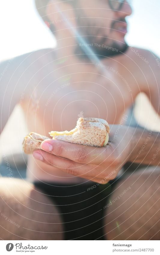 le sandwich II Lifestyle Stil Mensch maskulin Mann Erwachsene Essen Belegtes Brot Strand belegt sitzen Sonne Camargue Frankreich Südfrankreich Körper Shorts