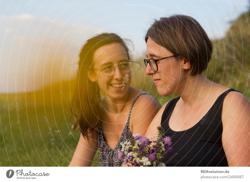 Zwei junge Frauen sitzen auf einer Wiese 18-30 Jahre Natur Liebe Schwester Glück Zusammensein Sommer Lebensfreude Erholung Freundschaft Zusammenhalt Unschärfe