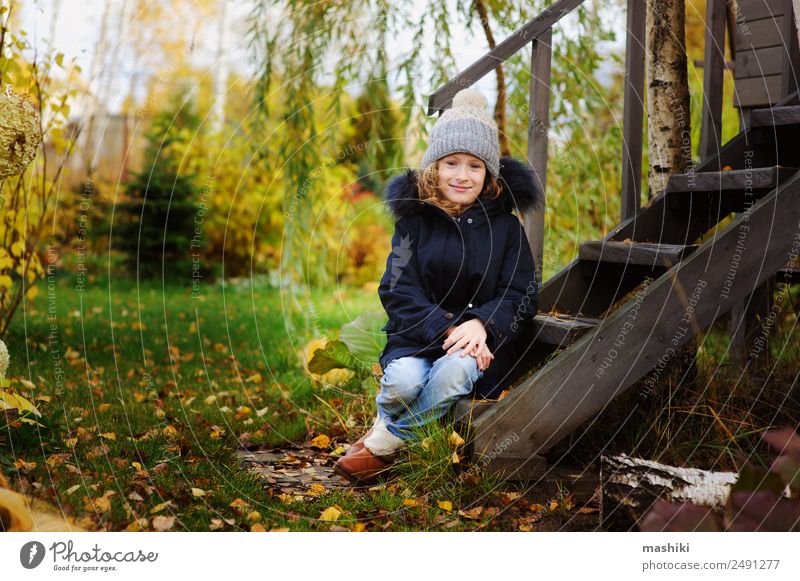 Herbstportrait eines glücklichen Kindes Mädchens im Garten sitzend Lifestyle Haus Natur Wärme Gras Blatt Holz Lächeln wild Spaziergang ländlich Land November