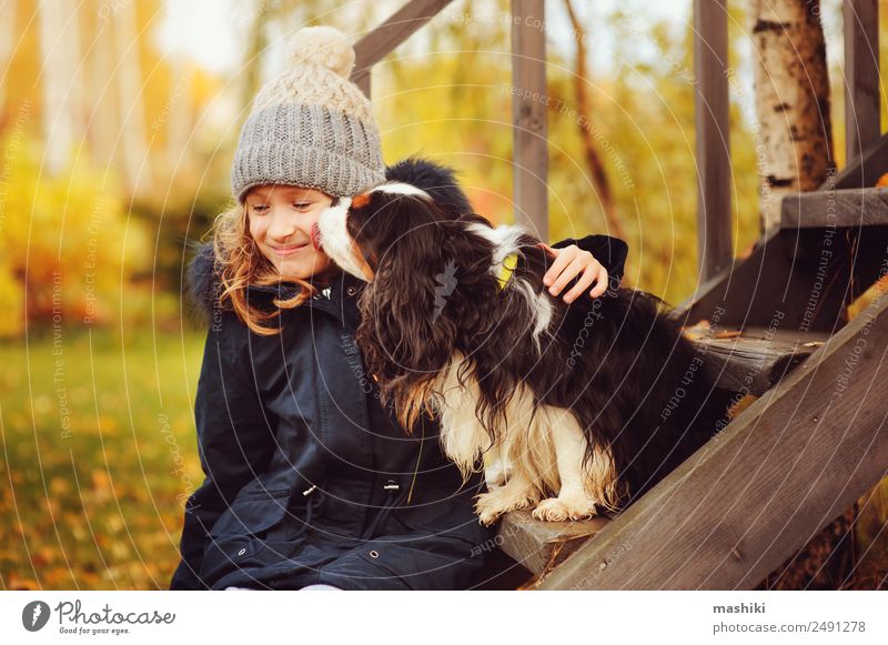 Herbstporträt eines glücklichen Kindmädchens, das mit ihrem Spanielhund spielt. Lifestyle Haus Garten Freundschaft Natur Wärme Gras Blatt Mantel Hut Haustier