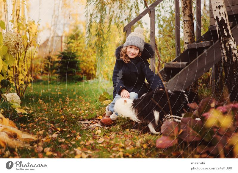 Herbstporträt eines glücklichen Kindes Mädchens, das mit ihrem Hund spielt. Lifestyle Freude Haus Garten Freundschaft Natur Mantel Hut Haustier Holz sitzen