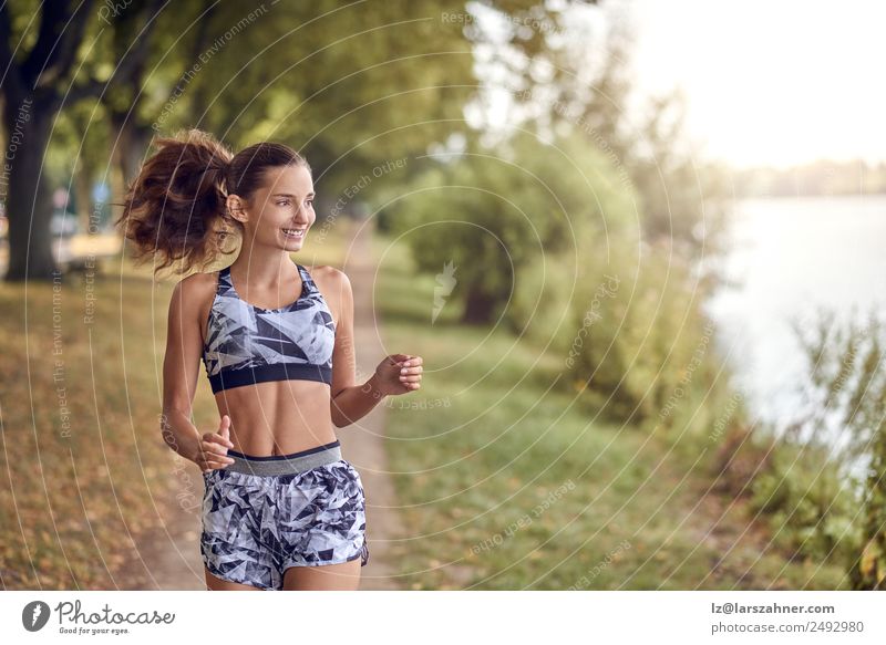 Fit, gesunde, sportliche Frau, die am Flussufer joggt. Lifestyle Glück Sommer Sport Joggen Erwachsene 1 Mensch 18-30 Jahre Jugendliche Wärme Park See Straße