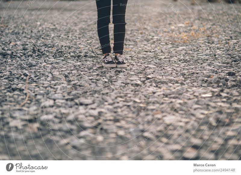 einsame, schwarz gekleidete Person, die auf einem Steinboden auf dem Land steht allein Hintergrund schwarze Jeans Fuß Jeanshose Landschaft Beine