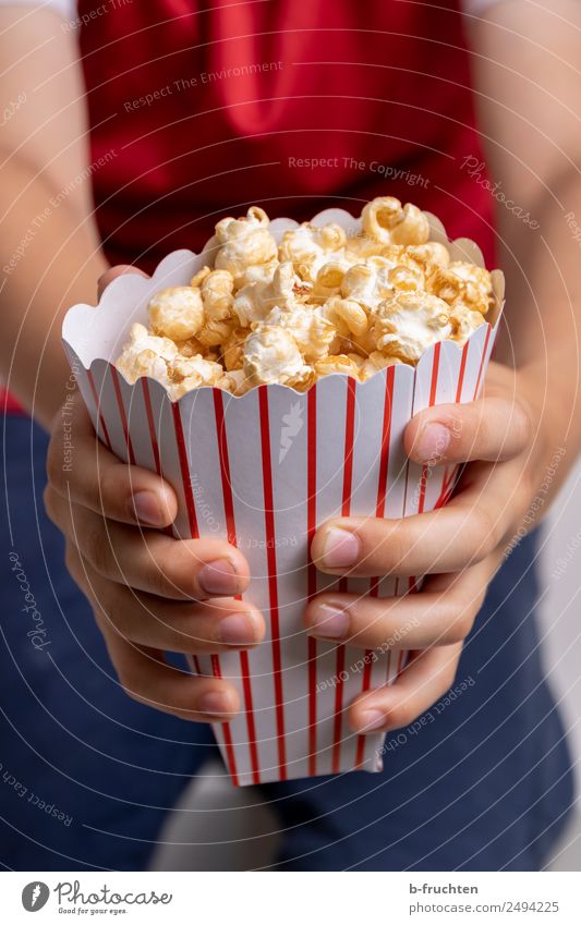 Eine Tüte Popcorn Süßwaren Fastfood Entertainment Junge Hand Finger 3-8 Jahre Kind Kindheit Veranstaltung Fernsehen festhalten frisch süß Popkorn Kino voll