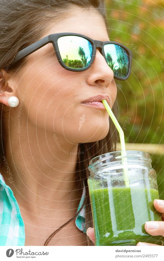 Frau mit Sonnenbrille, die im Freien grünen Gemüse-Smoothie trinkt. Frucht Ernährung Diät Getränk Saft Lifestyle Glück schön Sommer Garten Mensch Erwachsene