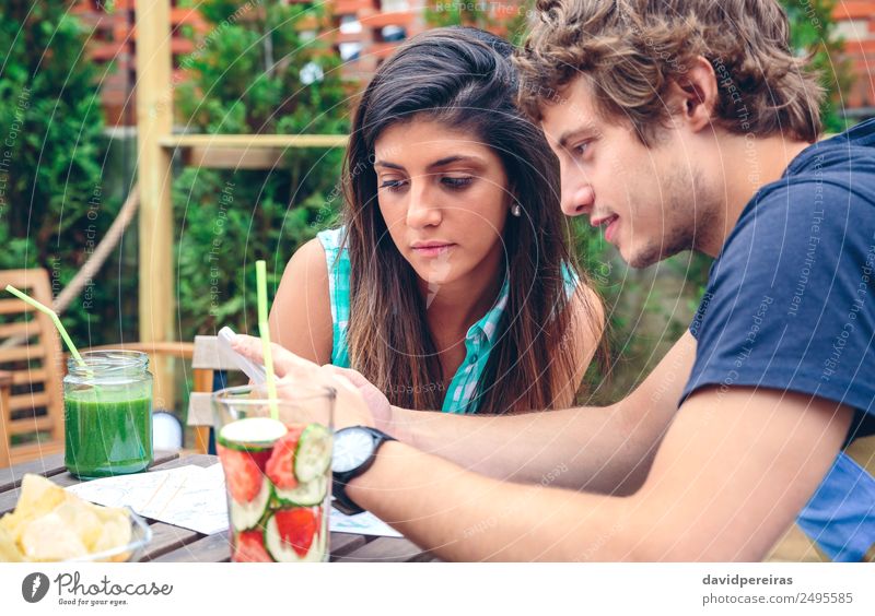 Junges Paar, das im Sommer im Freien ein Smartphone sucht. Gemüse Frucht Getränk Lifestyle Freude Glück Freizeit & Hobby Garten Tisch Telefon PDA