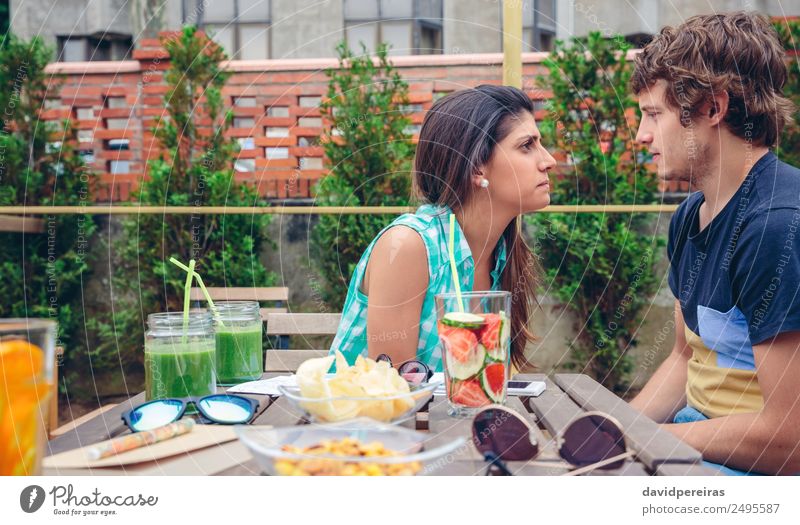 Ernste Frau, die sich mit einem Mann streitet, der hinter einem Tisch im Freien sitzt Gemüse Frucht Getränk Sommer Mensch Erwachsene Freundschaft Paar