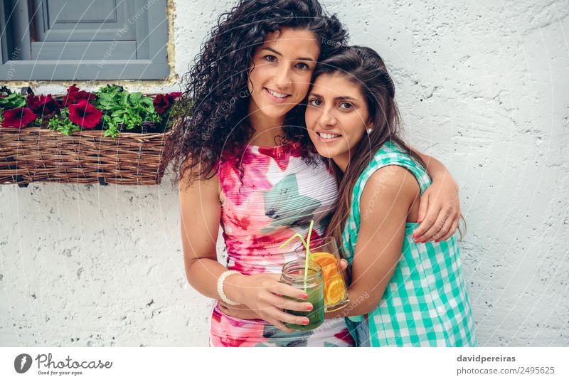 Zwei Frauen mit Getränken, die auf die Kamera schauen und die Kamera umarmen. Gemüse Frucht Saft Lifestyle Freude Glück Freizeit & Hobby Sommer Mensch