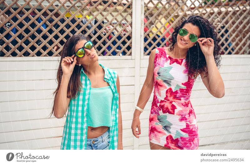 Frauen mit Sonnenbrille schauen auf die Kamera über dem Gartenzaun. Lifestyle Freude Glück Gesicht Freizeit & Hobby Sommer Spiegel Mensch Erwachsene