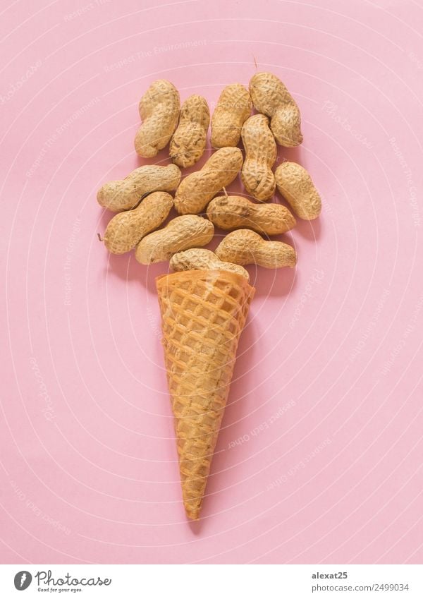 Eiscremekegel mit ungeschälten Erdnüssen auf rosa Hintergrund Lebensmittel Dessert Ernährung frisch natürlich Zapfen Sahne Zutaten vereinzelt Nut organisch