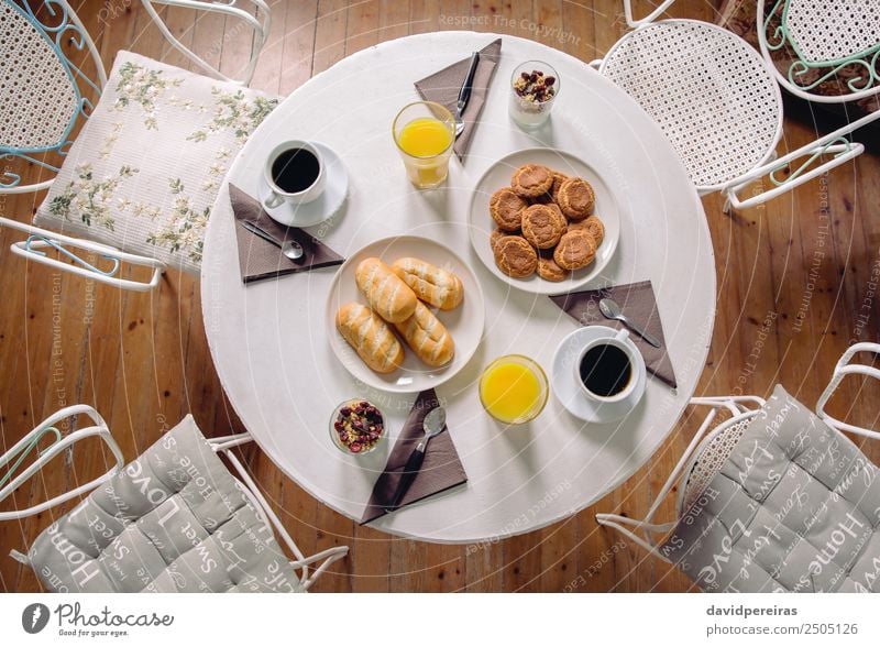 Draufsicht auf das gesunde Frühstück, das über einem Tisch serviert wird. Joghurt Frucht Croissant Saft Kaffee Teller Schalen & Schüsseln Löffel Restaurant