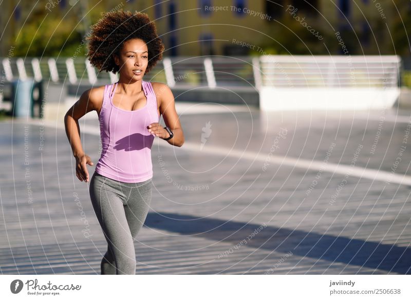 Schwarze Frau Afro-Frisur, die im Freien auf der Straße läuft. Lifestyle schön Haare & Frisuren Wellness Freizeit & Hobby Sport Joggen Mensch Junge Frau