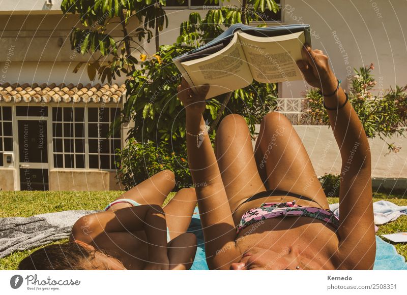 Mutter liest ein Buch mit ihrer kleinen Tochter im Pool beim Sonnenbaden. Sonnige Szene im Sommer. Familie lernen und lesen im Urlaub. Lifestyle Erholung