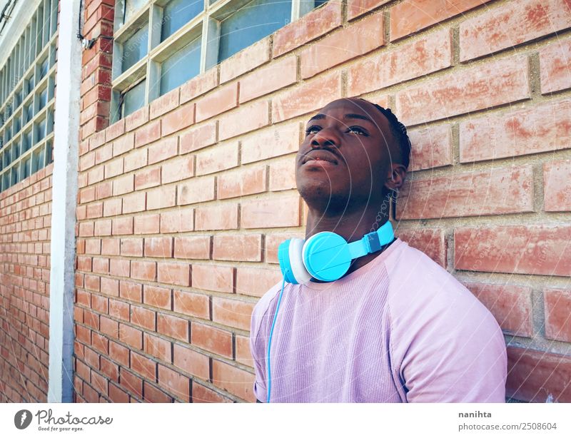 Junger schwarzer Mann gegen eine Ziegelmauer Lifestyle Stil Design Sinnesorgane Erholung Freizeit & Hobby Headset Kopfhörer Technik & Technologie