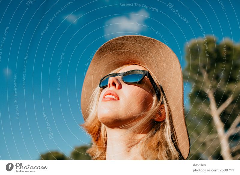 Süßes blondes Mädchen beim Sonnenbad in der Natur mit Sonnenbrille und Hut Lifestyle elegant Stil Freude schön Gesicht Wellness Erholung