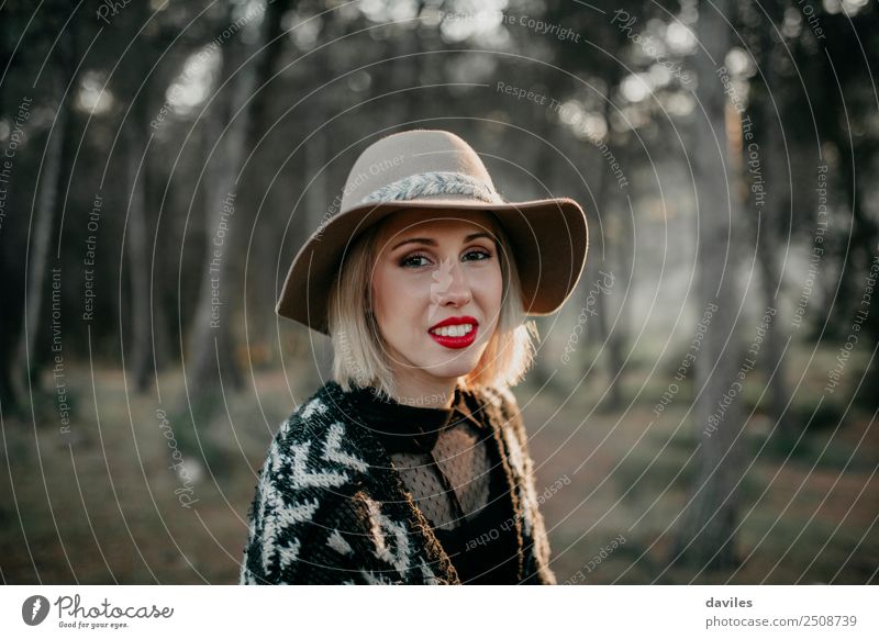 Porträt einer lächelnden blonden Frau mit Hut, während sie in der Natur spazieren geht und in die Kamera schaut. Lifestyle schön Ferien & Urlaub & Reisen