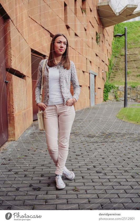 Junge trendige Frau über Steinmauer Hintergrund Lifestyle elegant Stil schön Mensch Erwachsene Herbst Straße Mode Bekleidung Jeanshose Jacke brünett stehen