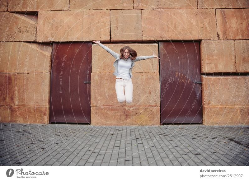Glückliche Frau springt vor einer Steinmauer im Hintergrund Lifestyle Freude schön Leben Freizeit & Hobby Freiheit Mensch Erwachsene Straße Mode Bekleidung