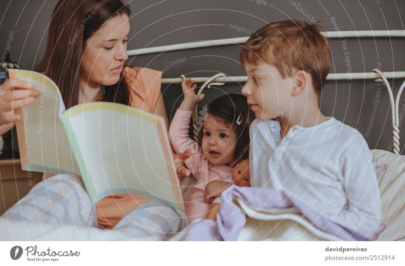 Mutter liest ihren Söhnen im Bett ein Buch vor. Lifestyle Freude Glück schön Erholung Freizeit & Hobby lesen Haus Schlafzimmer Kind Baby Junge Frau Erwachsene