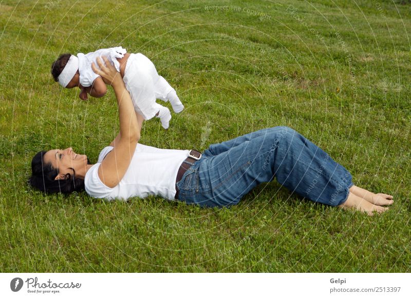 Eine weiße Frau mit einem schwarzen Baby. Glück Leben Mensch Erwachsene Mutter Gras Wiese Lächeln lachen Fröhlichkeit hell grün Gefühle Farbe Adoption