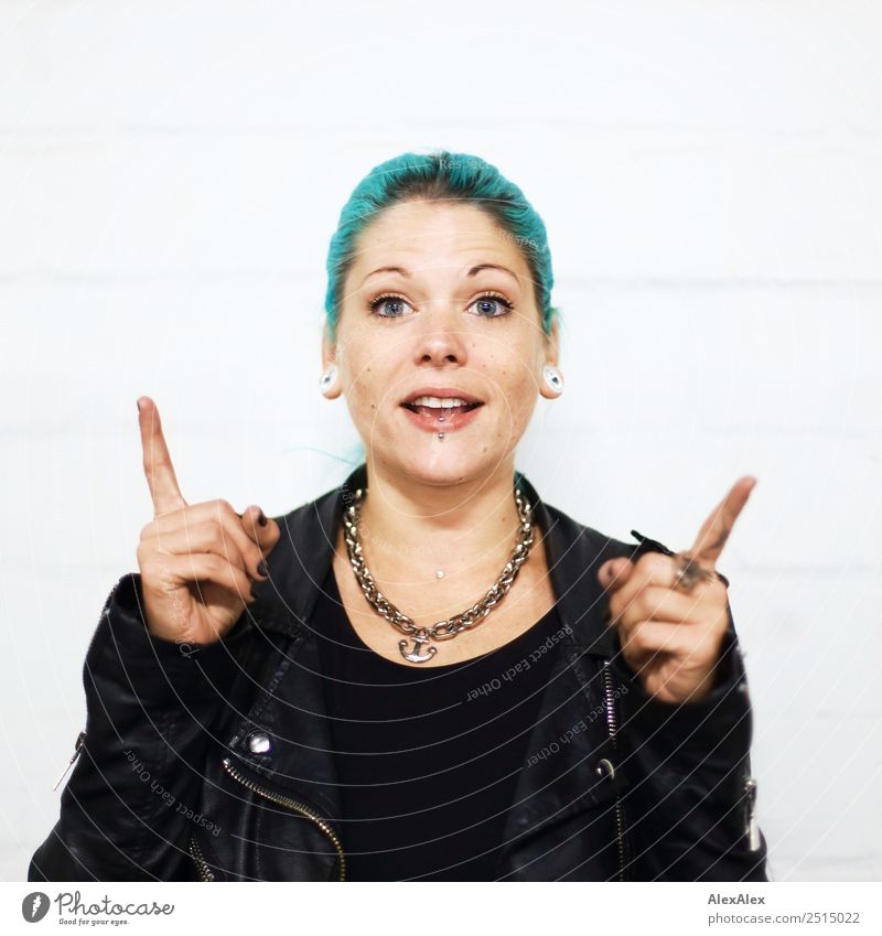 Junge Frau mit tükisen Haaren erklärt fingerzeigend schön Leben Jugendliche 18-30 Jahre Erwachsene Jugendkultur Lederjacke Accessoire Schmuck Piercing Ohrringe