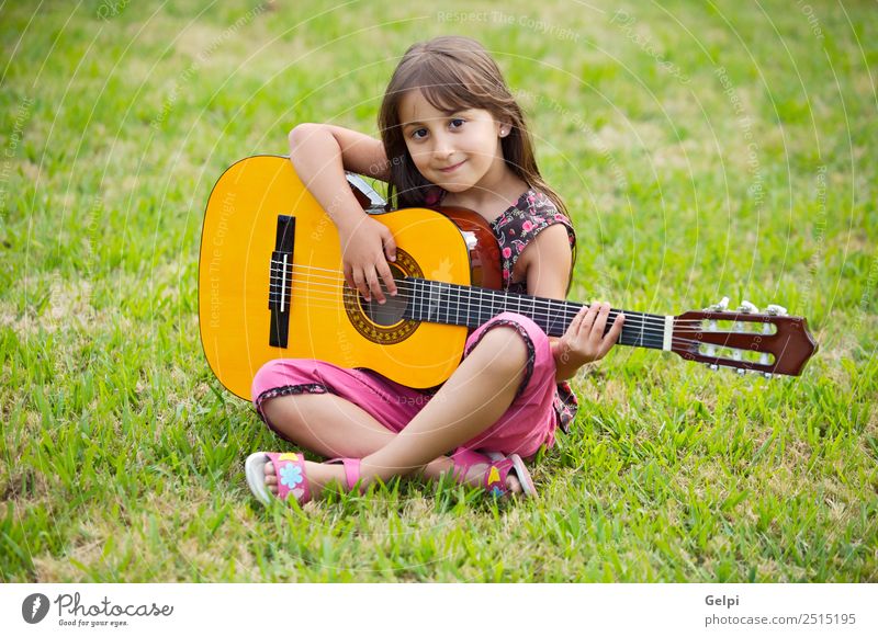Mädchen mit einer Gitarre im grünen Gras Musik Kind Schule Mensch Junge Musiknoten Blume rosa Schüler Spanisch gutaussehend Menschen Instrument Beautyfotografie