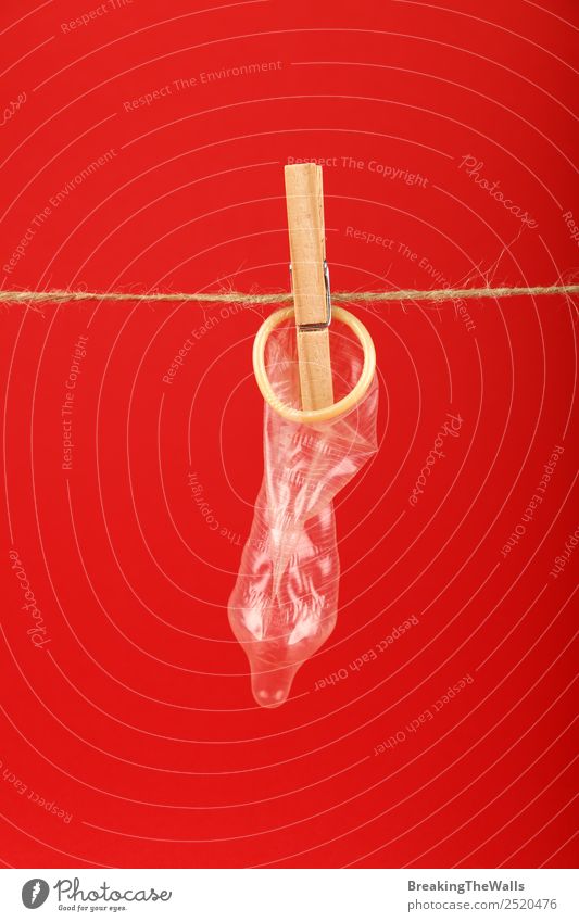 Nahaufnahme Kondom an der Waschlinie mit Wäscheklammer Gesundheit Gesundheitswesen Medikament retro rot Erholung Enttäuschung Farbe Frustration Sex Sexualität