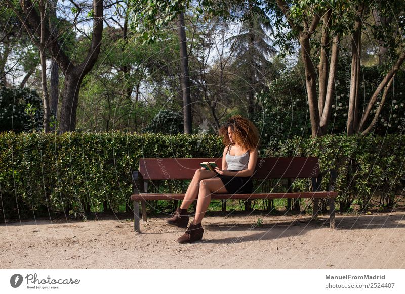 Afrofrau beim Lesen eines Buches auf einer Bank Lifestyle Glück schön Freizeit & Hobby lesen Sommer Schule lernen Mensch Frau Erwachsene Natur Baum Gras Park