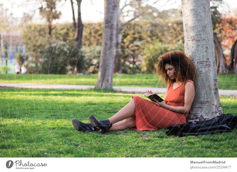 Afrofrau beim Lesen eines Buches im Freien Lifestyle Glück schön Freizeit & Hobby lesen Sommer Schule lernen Mensch Frau Erwachsene Natur Baum Gras Park