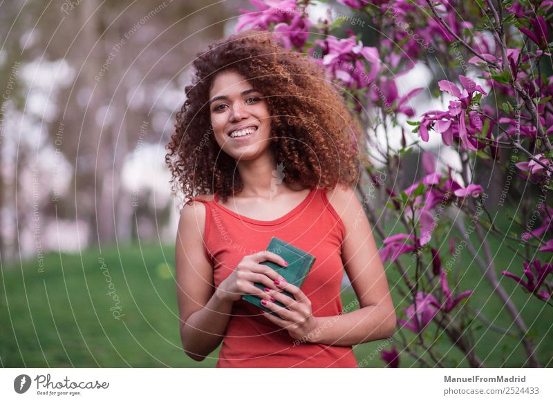 fröhliche Afrofrau, die ein Buch hält. Lifestyle Glück schön Freizeit & Hobby lesen Sommer Garten Schule lernen Fotokamera Mensch Frau Erwachsene Natur Baum